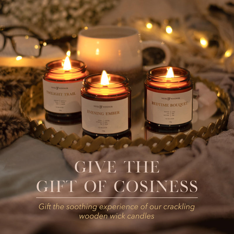Three lit Cosy candles on a mirrored tray with fairy lights on a night in